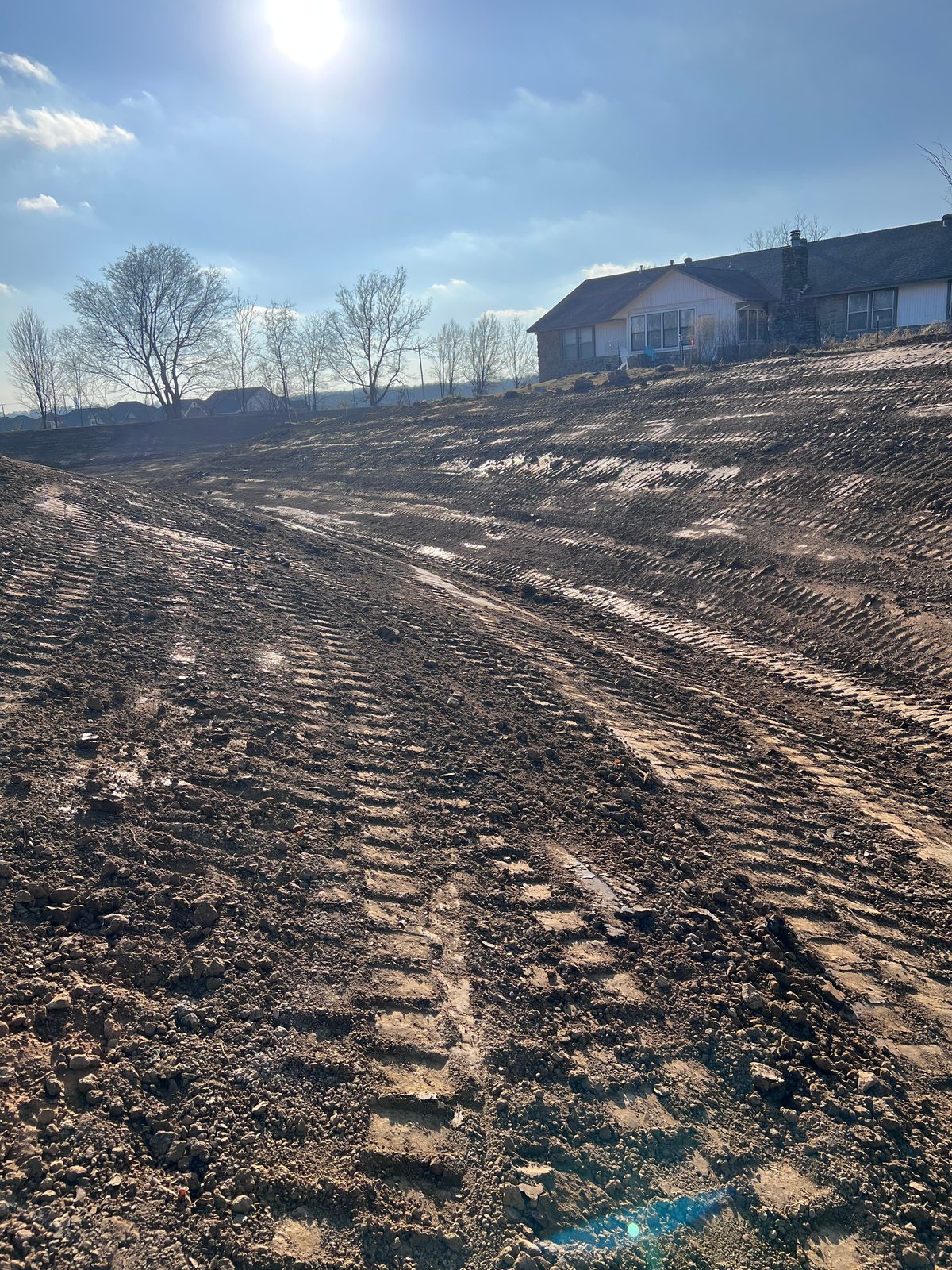 Freshly graded residential lot sloping toward a home