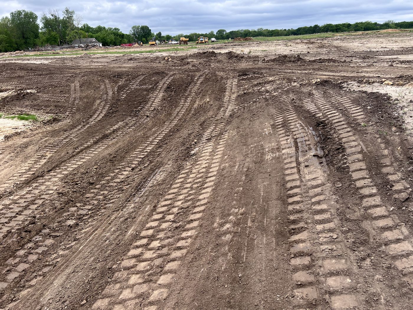 Large dirt lot graded and tracked smooth with equipment working in the background